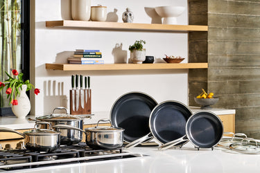 A HexClad pots and pans set displayed attractively on a gas stove and countertop.