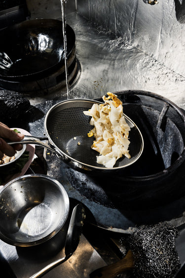 small wok cooking on a gas stove